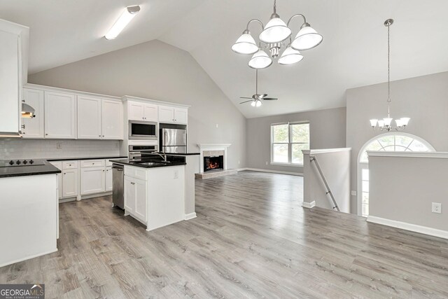 kitchen featuring light hardwood / wood-style flooring, stainless steel appliances, decorative backsplash, high vaulted ceiling, and white cabinets