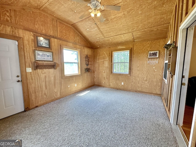 unfurnished room with lofted ceiling, plenty of natural light, light carpet, and wooden walls