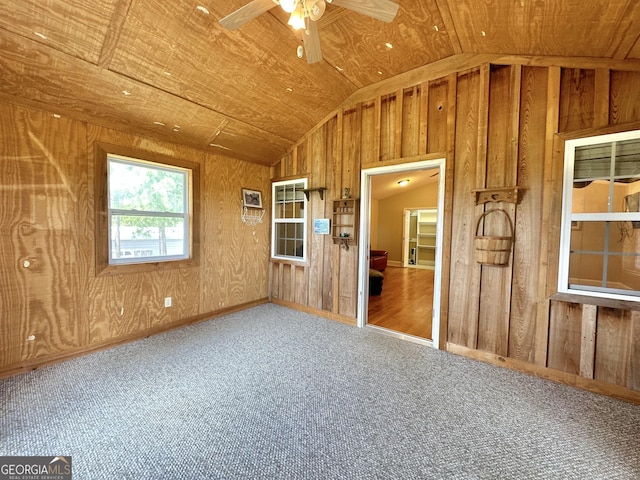 unfurnished room with a ceiling fan, lofted ceiling, wood ceiling, carpet flooring, and wood walls