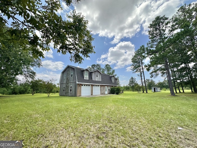 view of side of home featuring a garage, a shingled roof, a lawn, and a gambrel roof