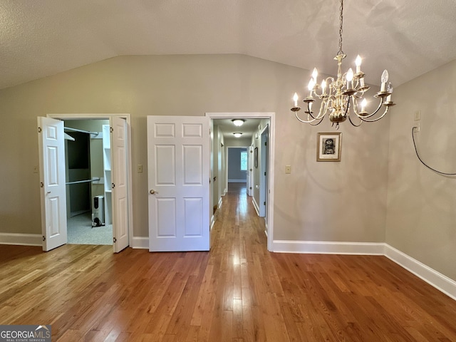 unfurnished dining area with vaulted ceiling, baseboards, and wood finished floors