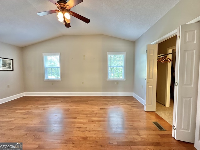 unfurnished bedroom featuring light wood-style floors, visible vents, vaulted ceiling, and baseboards