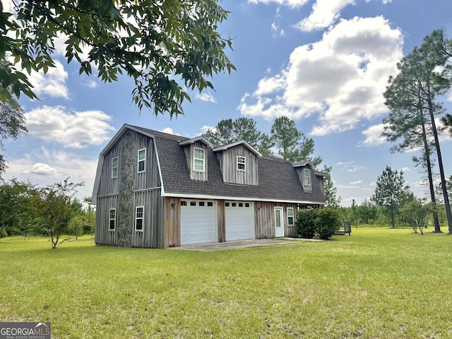 view of side of property featuring a yard, a shingled roof, an attached garage, a gambrel roof, and driveway