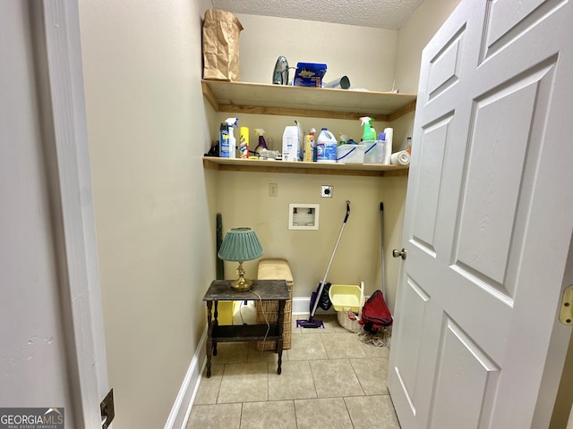 clothes washing area with hookup for a washing machine, light tile patterned flooring, electric dryer hookup, laundry area, and baseboards