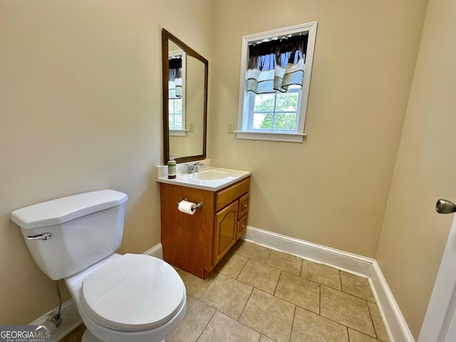 half bathroom featuring vanity, toilet, and baseboards