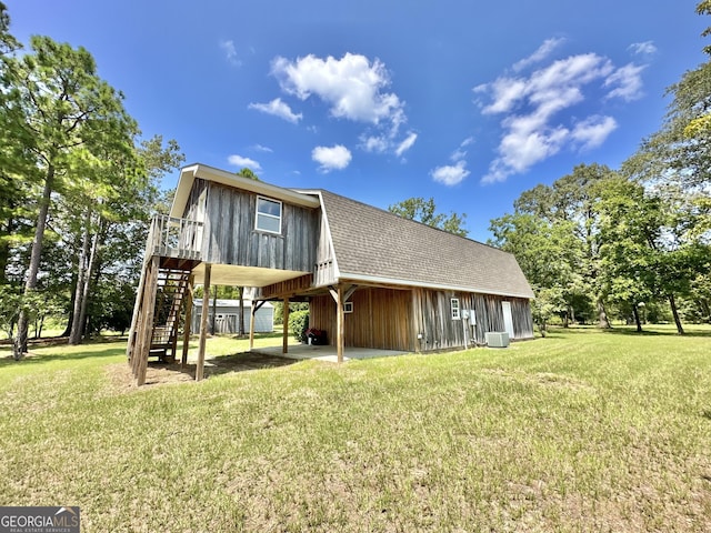 exterior space featuring roof with shingles, stairs, a gambrel roof, and a yard