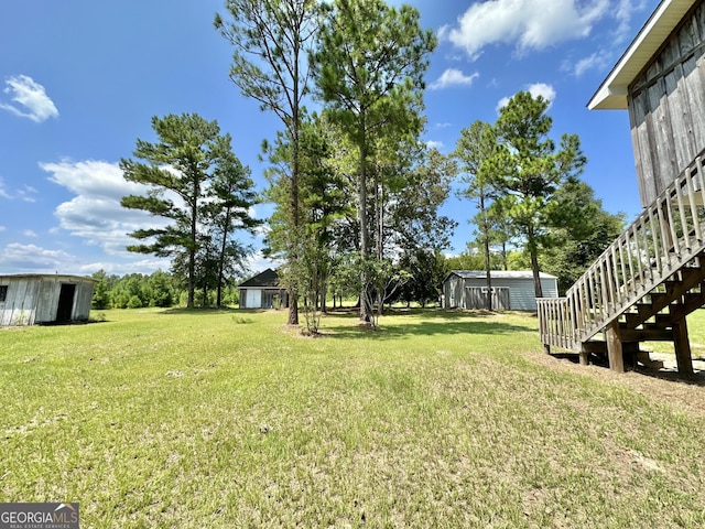 view of yard featuring an outbuilding, a storage unit, and stairway