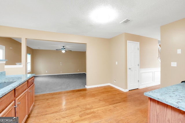 kitchen with light wood-type flooring, open floor plan, visible vents, and ceiling fan