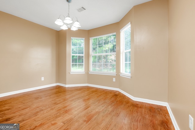 empty room featuring a chandelier and wood-type flooring