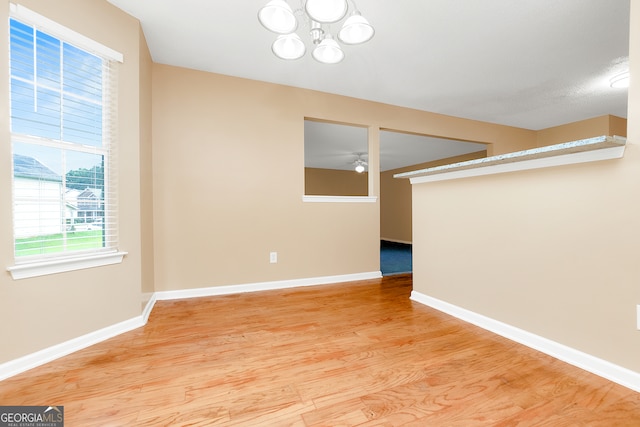 spare room with hardwood / wood-style flooring and ceiling fan with notable chandelier