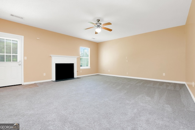 unfurnished living room with visible vents, a fireplace with raised hearth, baseboards, ceiling fan, and carpet floors