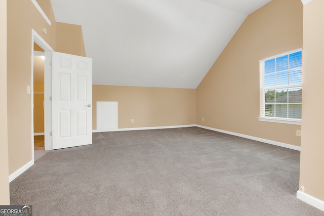 additional living space featuring vaulted ceiling and light carpet