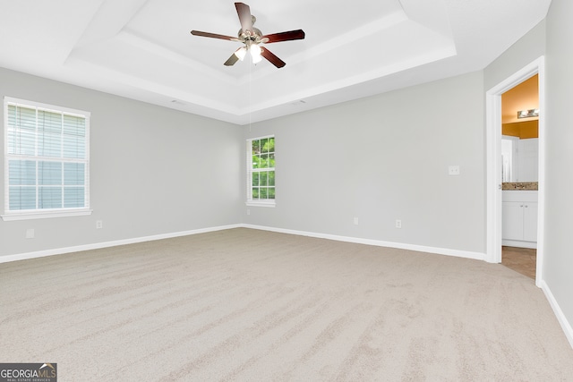 carpeted spare room with ceiling fan and a raised ceiling