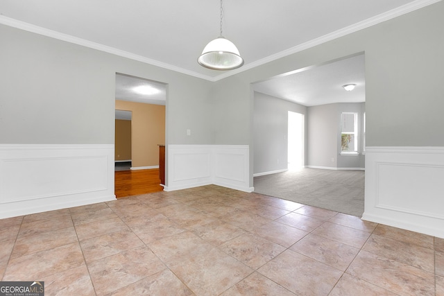 empty room featuring a wainscoted wall, light tile patterned floors, and ornamental molding