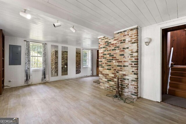 unfurnished room featuring beamed ceiling, a wealth of natural light, wood-type flooring, and electric panel