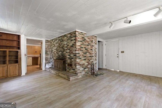 unfurnished living room with a fireplace, light hardwood / wood-style flooring, brick wall, and rail lighting