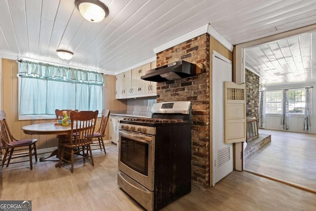 kitchen featuring light hardwood / wood-style floors, wall chimney range hood, ornamental molding, and gas stove