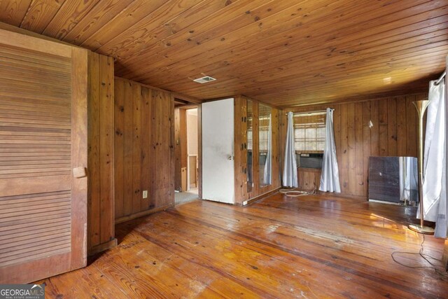 unfurnished living room with hardwood / wood-style flooring and wooden walls