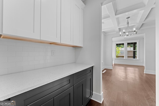 kitchen with backsplash, beam ceiling, hardwood / wood-style flooring, coffered ceiling, and white cabinetry