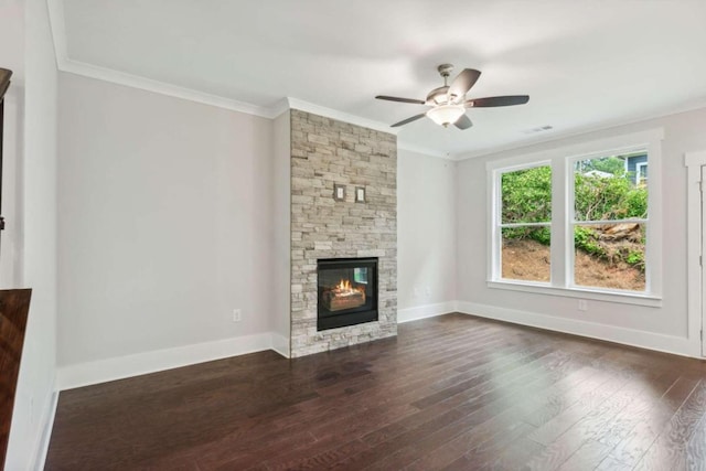 unfurnished living room with ceiling fan, dark wood-type flooring, a stone fireplace, and crown molding