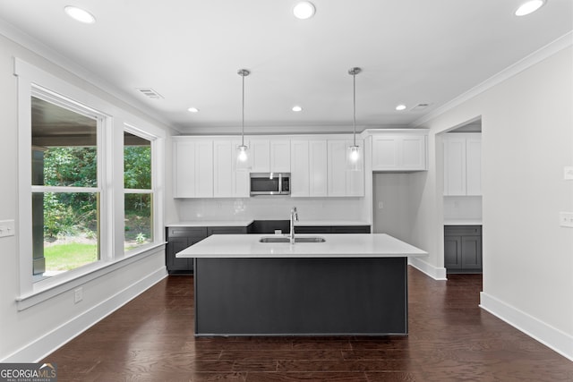 kitchen with sink, dark hardwood / wood-style floors, white cabinets, pendant lighting, and a center island with sink