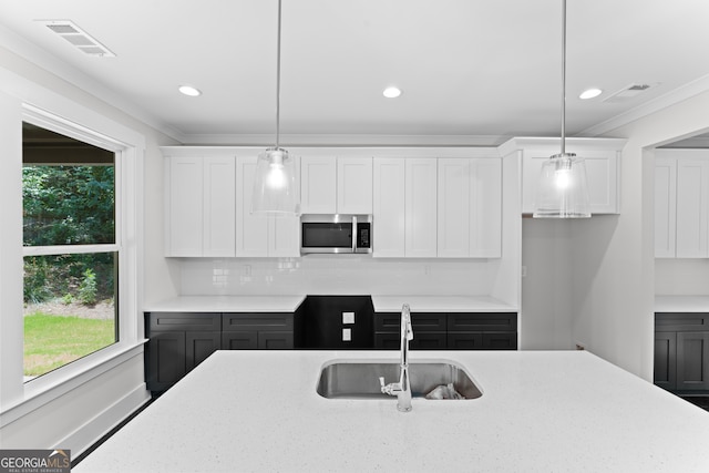 kitchen featuring white cabinets, sink, crown molding, and pendant lighting