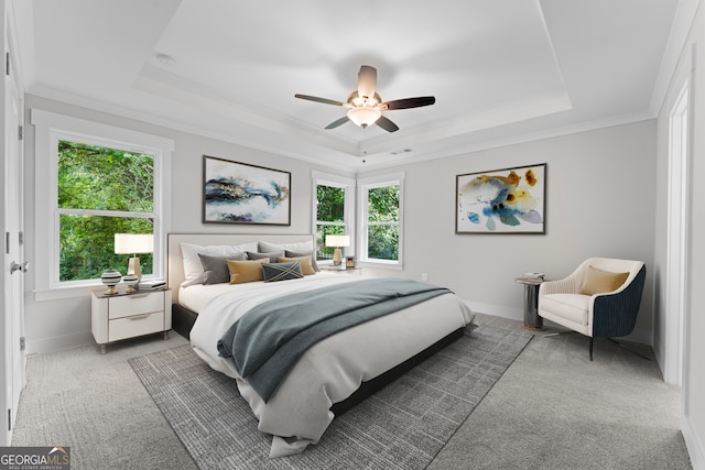 bedroom with ceiling fan, a raised ceiling, ornamental molding, and light carpet