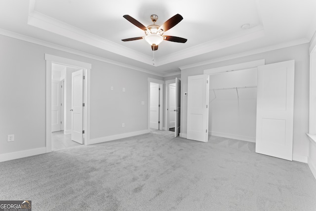 unfurnished bedroom featuring a tray ceiling, ceiling fan, and light colored carpet