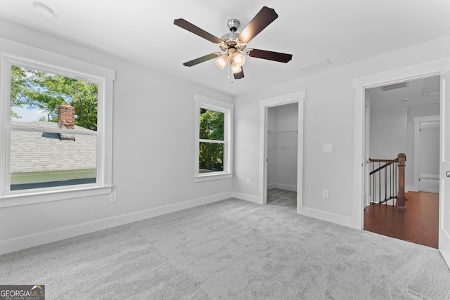 unfurnished bedroom with carpet floors, a closet, ceiling fan, and a walk in closet