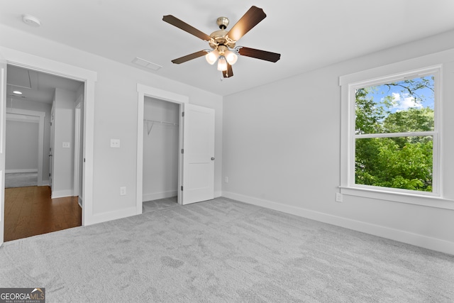 unfurnished bedroom featuring ceiling fan, light colored carpet, a closet, and multiple windows