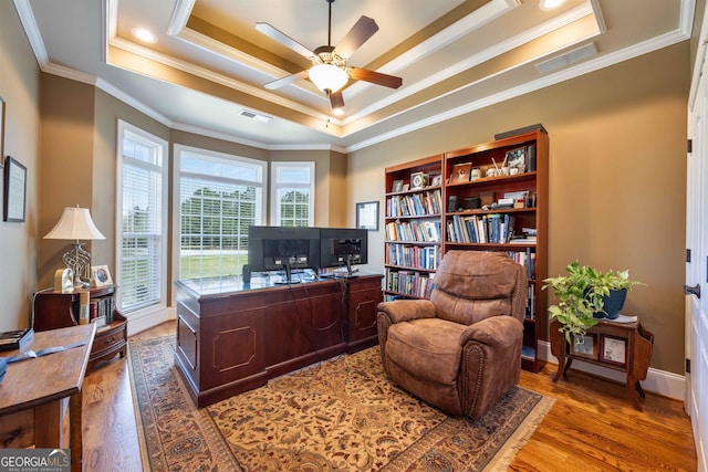 home office featuring ceiling fan, a raised ceiling, hardwood / wood-style flooring, and ornamental molding