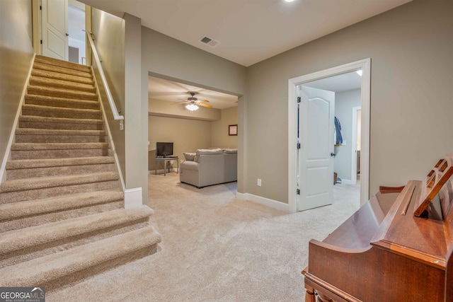 stairs with ceiling fan and carpet floors