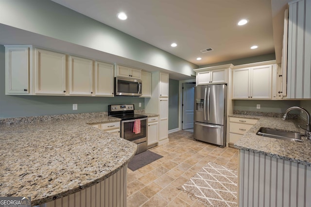 kitchen featuring sink, appliances with stainless steel finishes, light stone countertops, light tile patterned floors, and kitchen peninsula