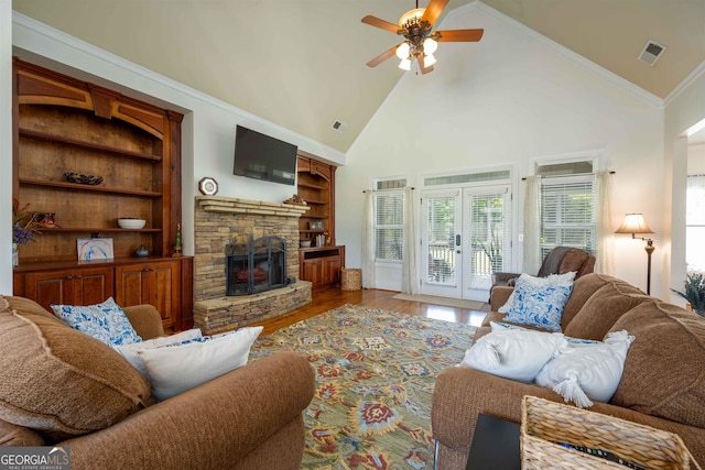 living room with crown molding, high vaulted ceiling, wood-type flooring, ceiling fan, and a stone fireplace