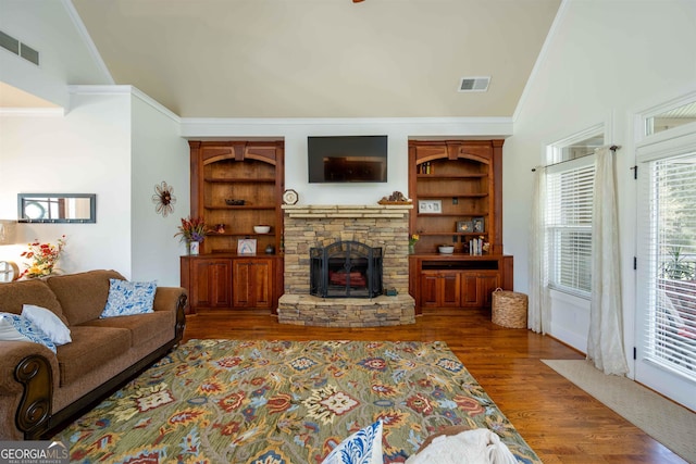 living room with ornamental molding, built in features, high vaulted ceiling, dark hardwood / wood-style flooring, and a stone fireplace