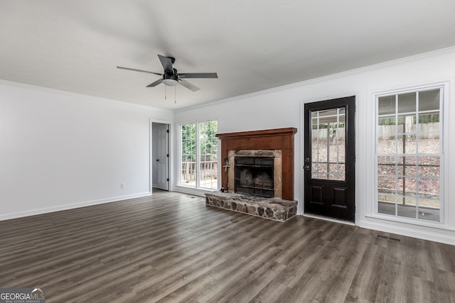 unfurnished living room with a wealth of natural light, ceiling fan, a stone fireplace, and dark hardwood / wood-style flooring