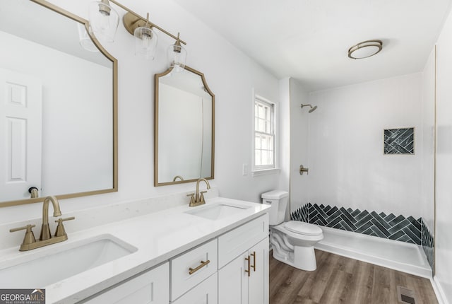 bathroom with a shower, toilet, hardwood / wood-style floors, and vanity