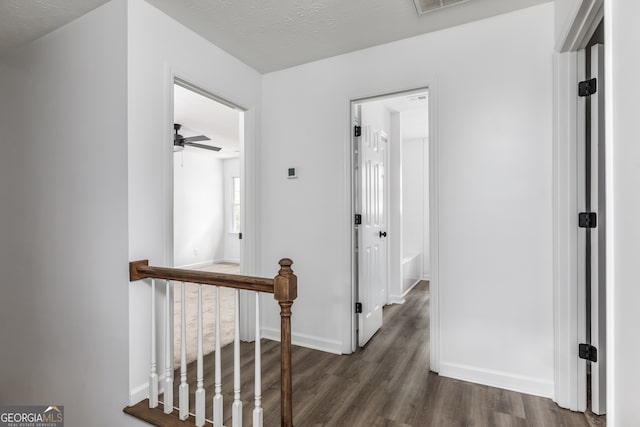 hallway with dark wood-type flooring and a textured ceiling