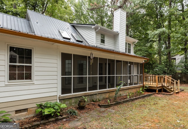 rear view of property with a wooden deck and a sunroom