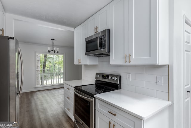 kitchen with a notable chandelier, crown molding, white cabinetry, light hardwood / wood-style flooring, and stainless steel appliances