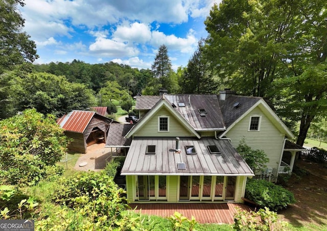 rear view of property featuring a chimney and metal roof