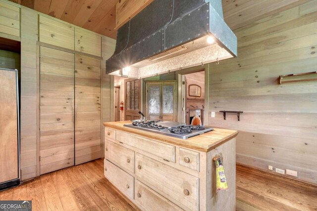 kitchen with light hardwood / wood-style flooring, wooden walls, island exhaust hood, and wooden counters