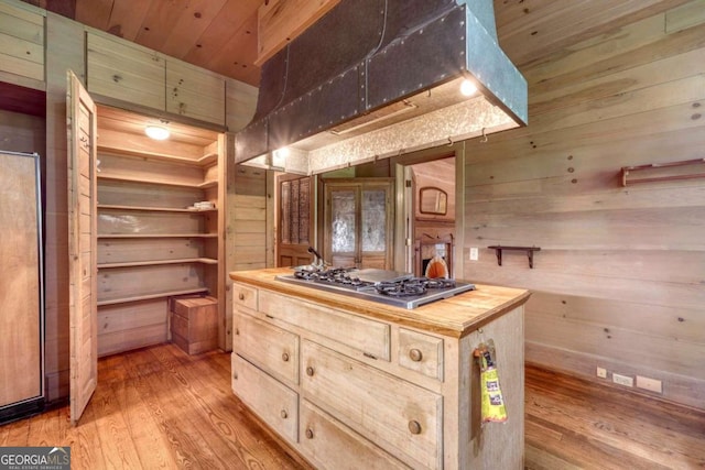 kitchen with stainless steel gas cooktop, wooden counters, ventilation hood, and wooden walls