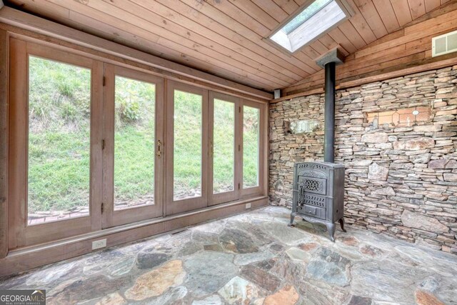 unfurnished sunroom featuring wood ceiling, a wood stove, and lofted ceiling with skylight