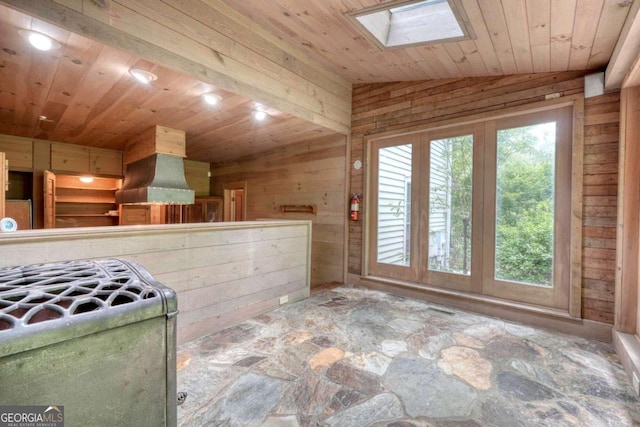 kitchen featuring wooden ceiling, lofted ceiling with skylight, wooden walls, and exhaust hood