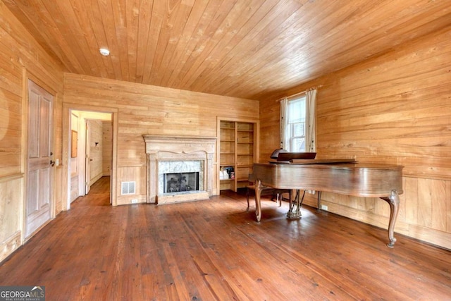 unfurnished living room featuring wooden walls, a high end fireplace, hardwood / wood-style floors, and wooden ceiling