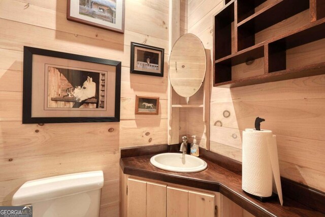 bathroom with wooden walls, toilet, and vanity