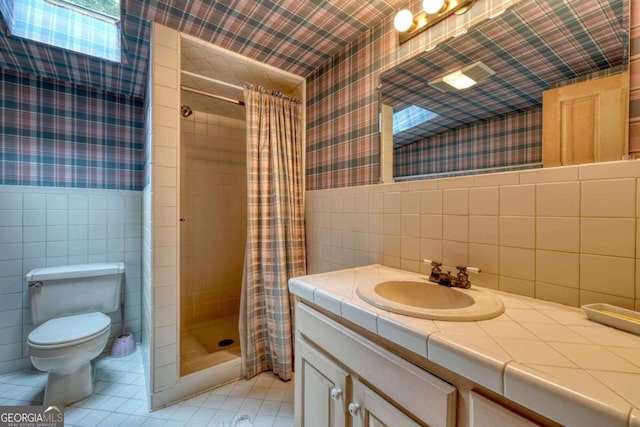 bathroom with toilet, wallpapered walls, tile walls, and wainscoting