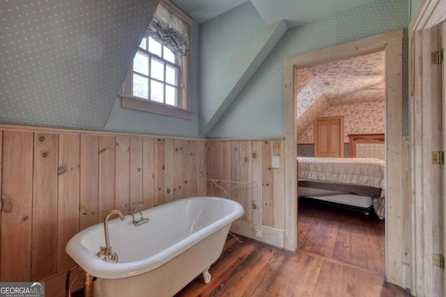 bathroom featuring a washtub, lofted ceiling, wood walls, and wood-type flooring