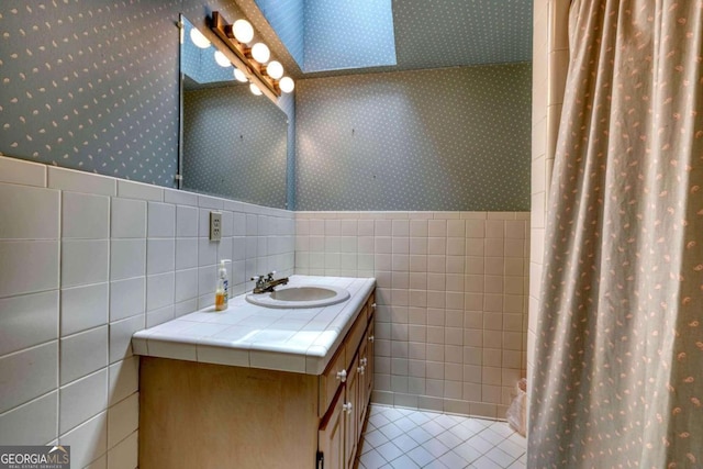 bathroom featuring curtained shower, tile patterned flooring, vanity, and tile walls